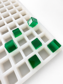 Angled view of the 2.85mL cube gummy mold with 315 cavities and translucent emerald green gummy samples
