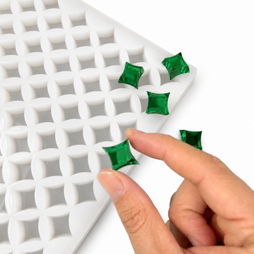 Hand pressing an emerald green gummy in a 2mL star gummy mold with 192 cavities on a white background