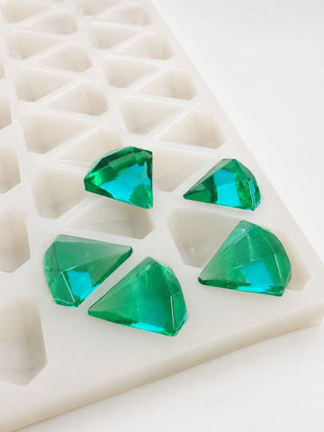 Close angled view of a 3.5mL diamond gummy mold with 173 cavities and emerald green faceted gummies