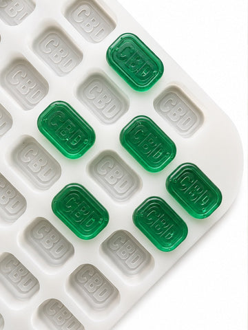 Top-angle view of a 4mL brick gummy mold with 185 cavities and emerald green CBD gummies on a white background